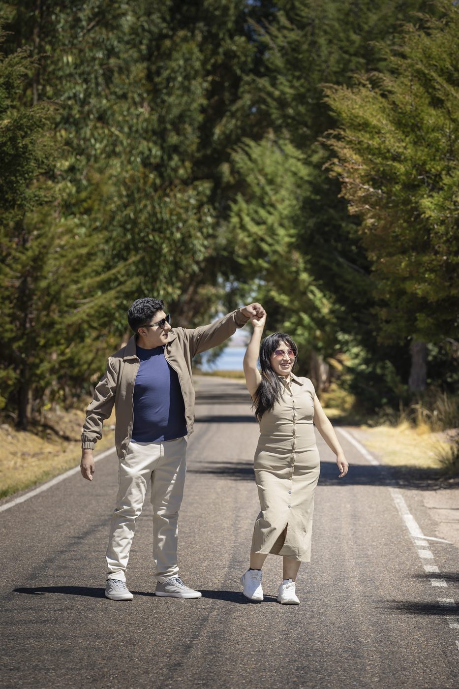 Los novios bailan en medio de una carretera rodeada de árboles