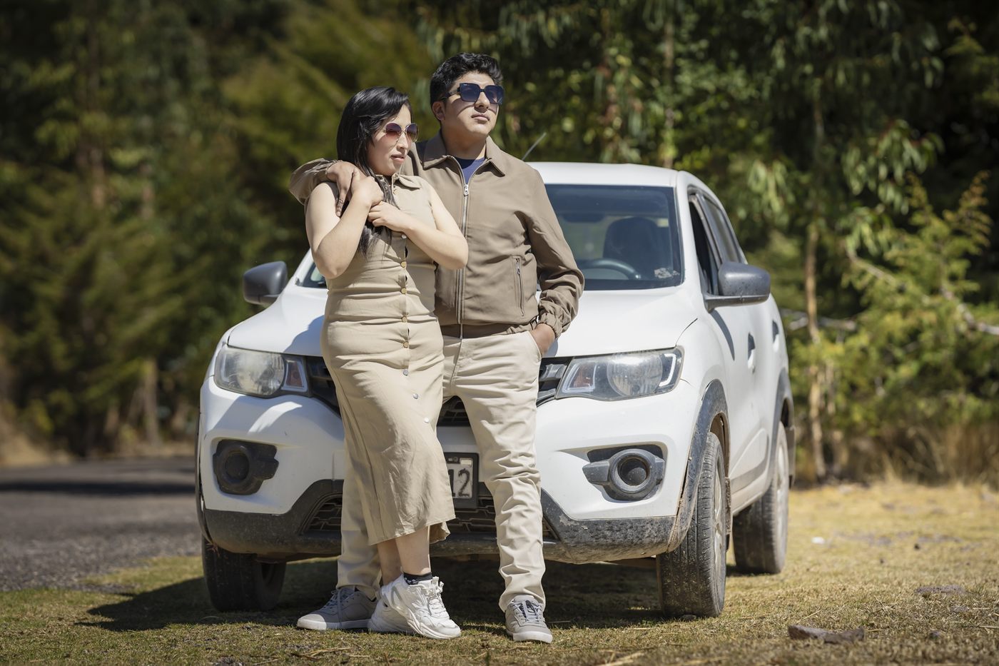 Los novios abrazados apoyados en una camioneta blanca